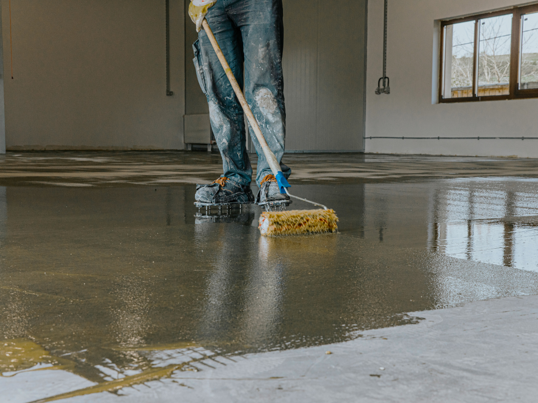 Worker preparing the floor for epoxy application in a commercial space, ensuring a clean and smooth surface.