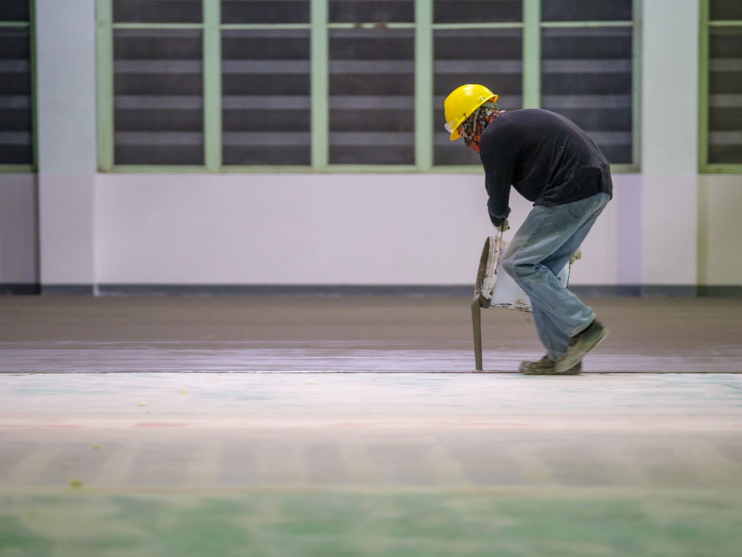 Technician from Spring Epoxy Flooring Pros applying a coating to a concrete surface for a smooth and durable epoxy finish.