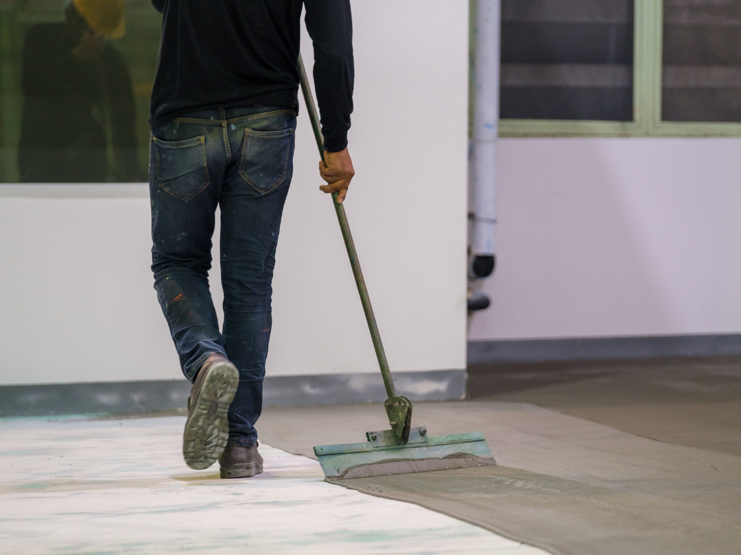 Spring Epoxy Flooring Pros technician preparing a large indoor concrete surface for epoxy application with specialized tools.